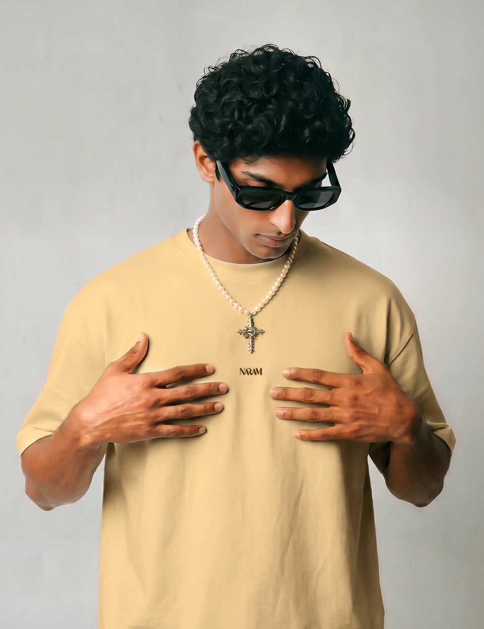 beige-oversized-tshirt-front-model-naram-logo.jpgFront view of Naram Babbar Sher beige oversized tshirt on model with embroidered Naram chest logo, styled with pearl necklace, Indian streetwear