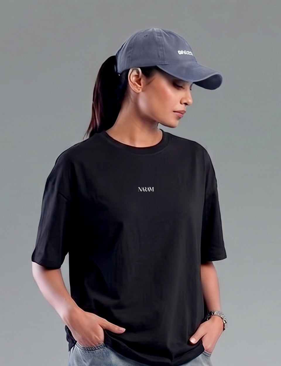 cap-streetwear-india.jpgWoman wearing Naram oversized black t-shirt with grey cap.indian streetwear brand minimal design