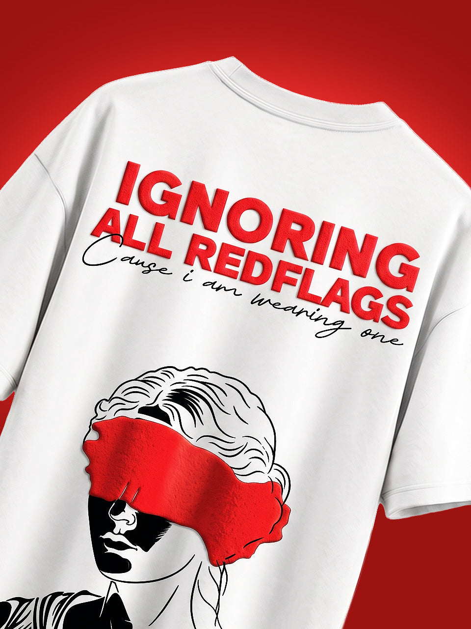 Close-up of Ignoring All Redflags bold red puff print text and blindfolded woman illustration on back of Naram white oversized tshirt, red background