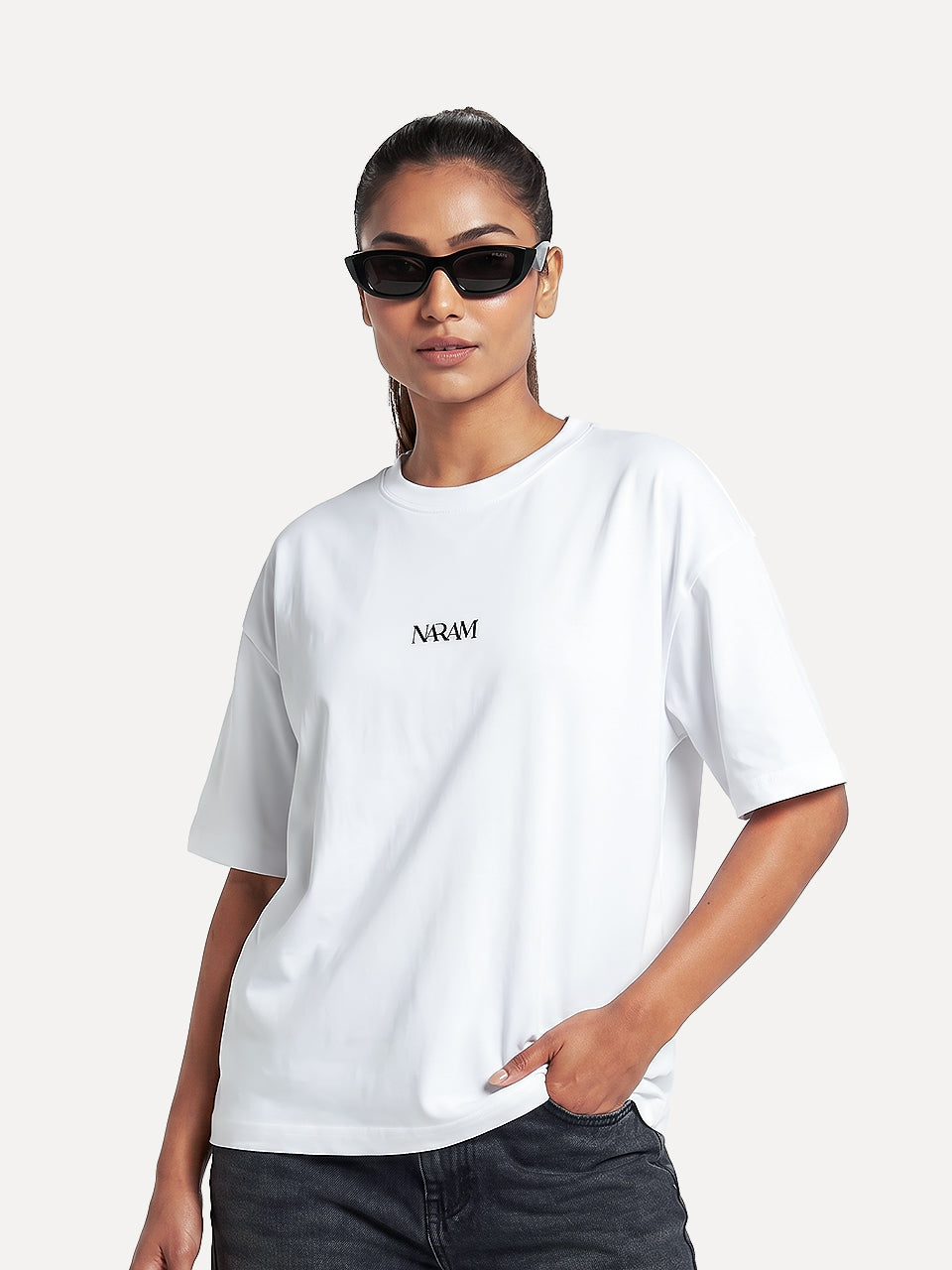 Front view of Naram Red Flag white oversized tshirt on female model with black Naram chest logo, styled with dark jeans, women Indian streetwear
